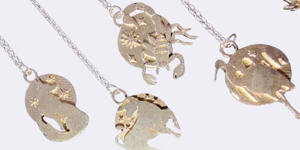 a group of silver pendants with zodiac symbols